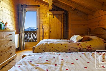 A bedroom in a log cabin with two beds and a dresser