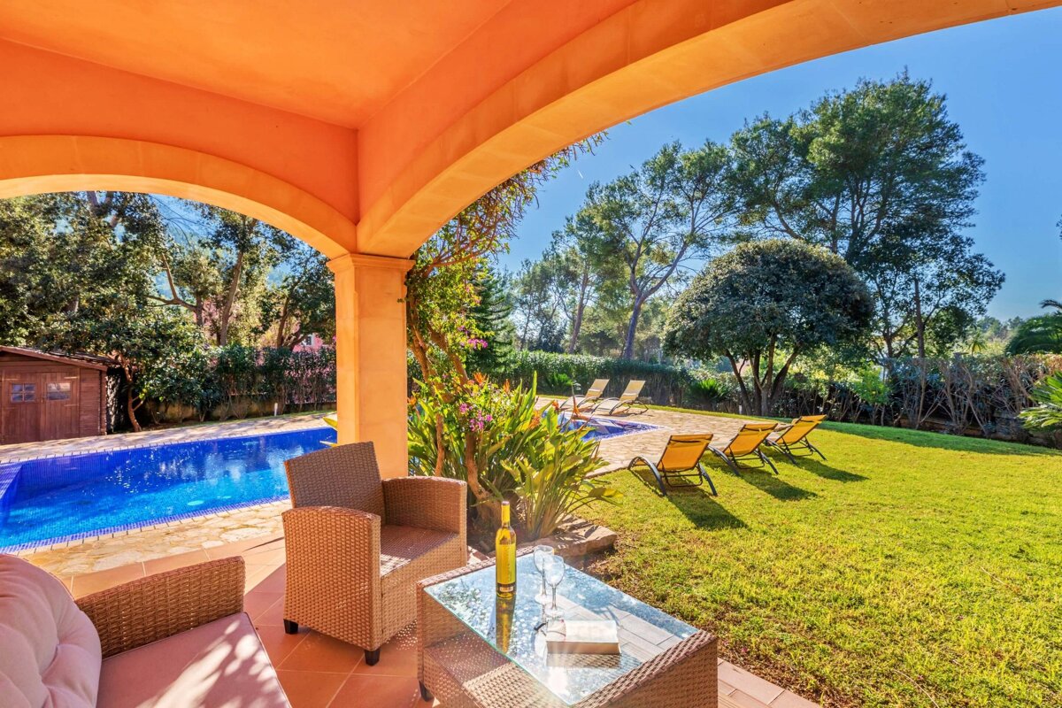 A patio with chairs and a table with a bottle of wine on it