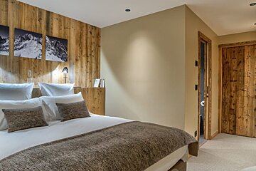 A bedroom with a wooden wall and a bed