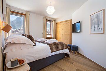 A bedroom with a large bed and a flat screen tv