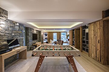 A game room with a foosball table and a computer