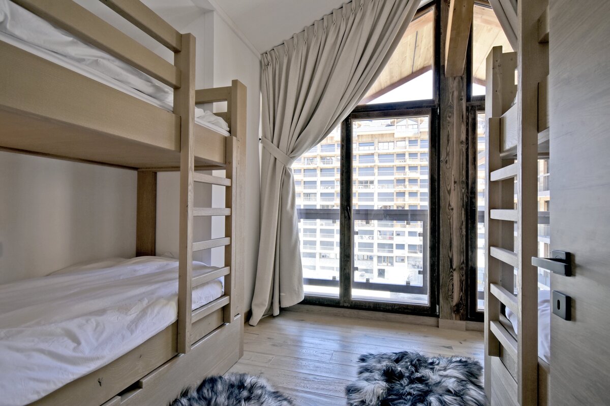 A room with bunk beds and a window with curtains