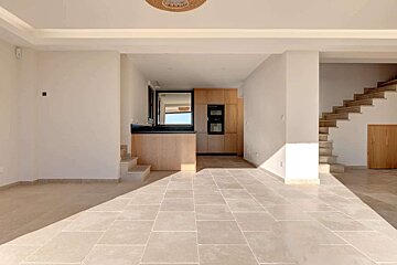 An empty room with stairs leading up to a kitchen