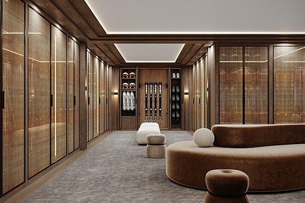 A luxurious, warm-toned walk-in closet featuring elegant wood cabinets, ski equipment displays, plush seating, and soft ambient lighting.