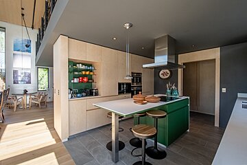 A kitchen with a green island and stools