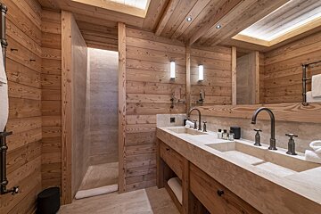 A bathroom with two sinks and a walk in shower