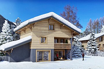 A cozy wooden ski chalet with a snow-covered roof in a beautiful winter landscape under a bright blue sky.
