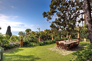 A table and chairs in a garden with a view of the ocean