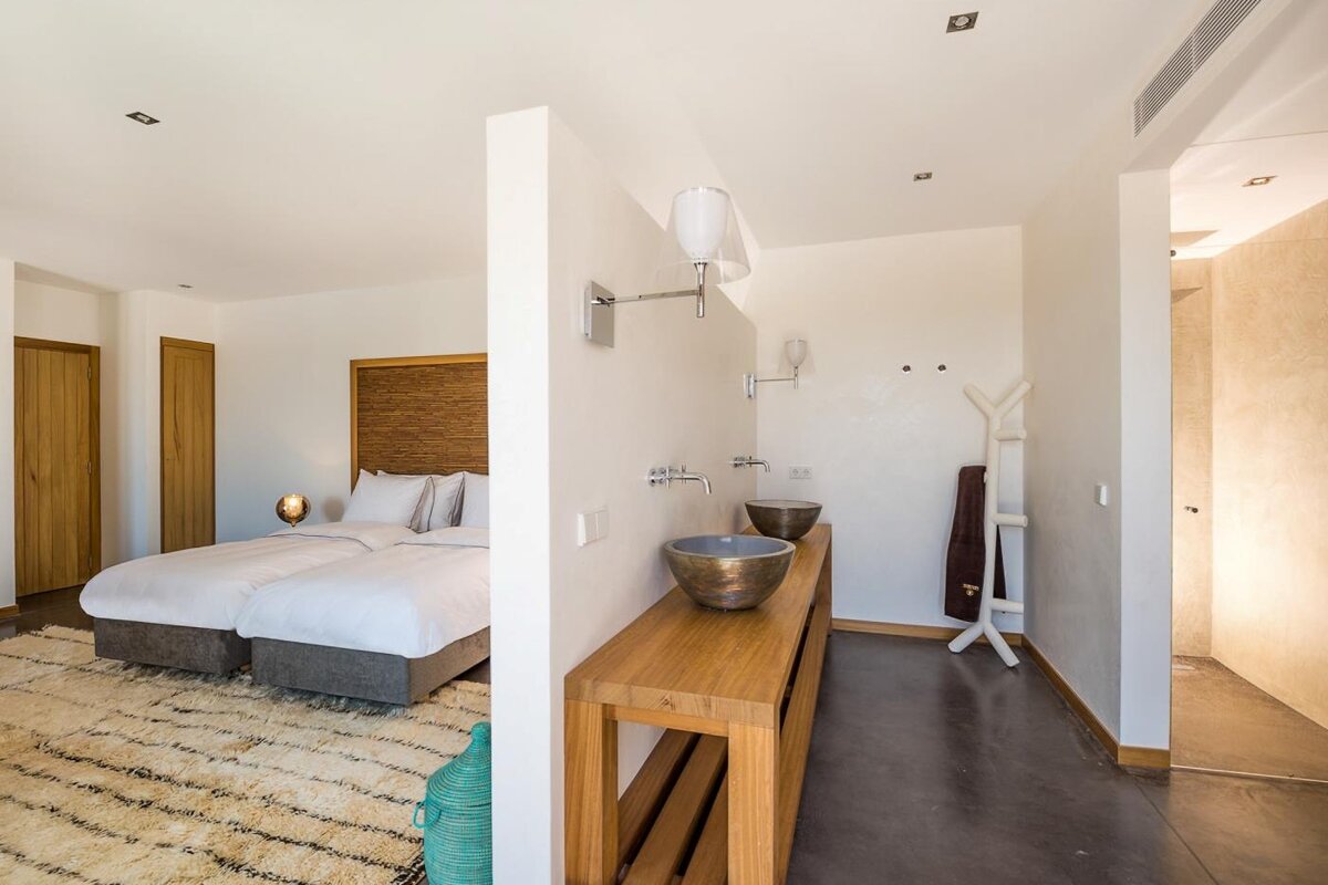 A bedroom with two beds and a bathroom with two sinks