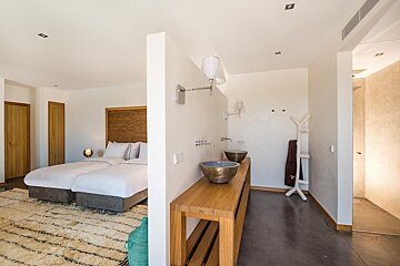 A bedroom with two beds and a bathroom with two sinks