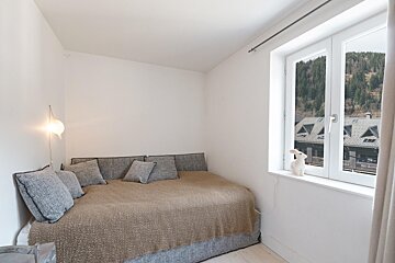 A bedroom with a bed and a window with a stuffed animal on the window sill