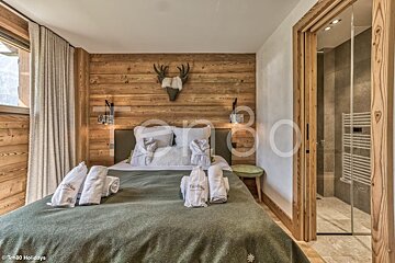 A bedroom with a large bed and a deer head on the wall