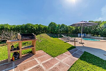A patio area with a grill and an umbrella