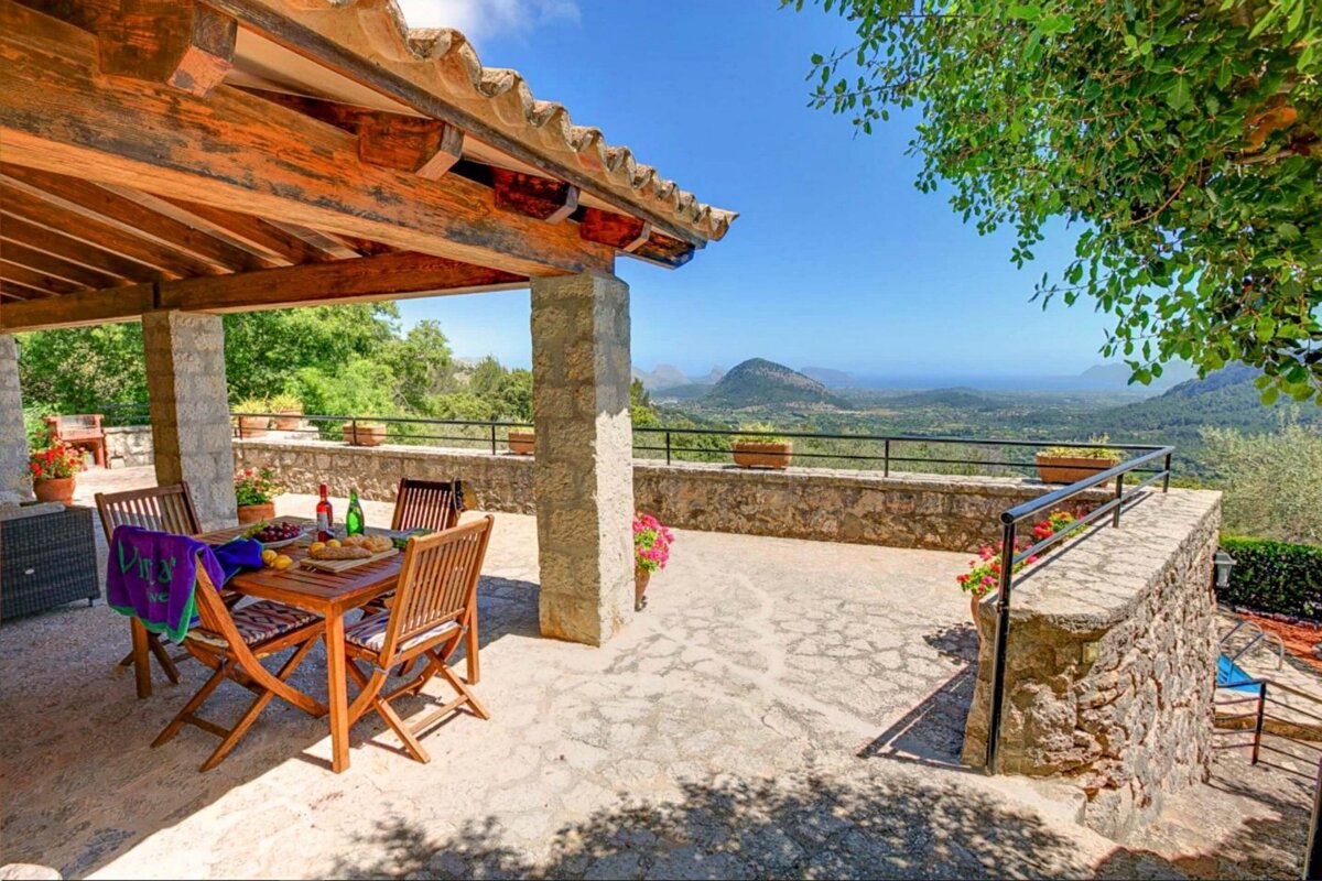 A patio with a table and chairs and a view of mountains