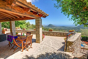 A patio with a table and chairs and a view of mountains