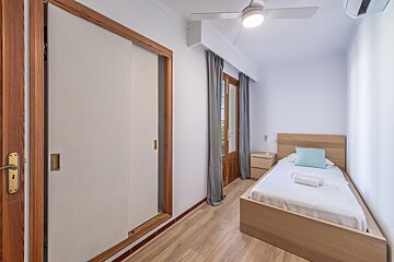 A bedroom with a single bed and a ceiling fan