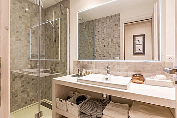 A bathroom with a sink a mirror and a walk in shower