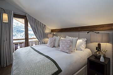 A bedroom with a large bed and two lamps