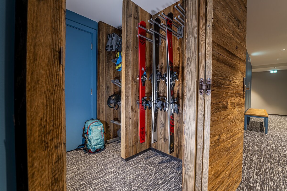 A row of skis are hanging on a wooden wall