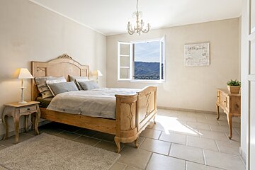 A bedroom with a bed and a window with mountains in the background