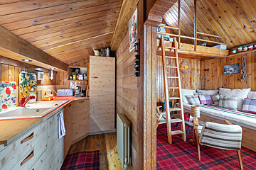 A kitchen with a ladder leading up to a loft