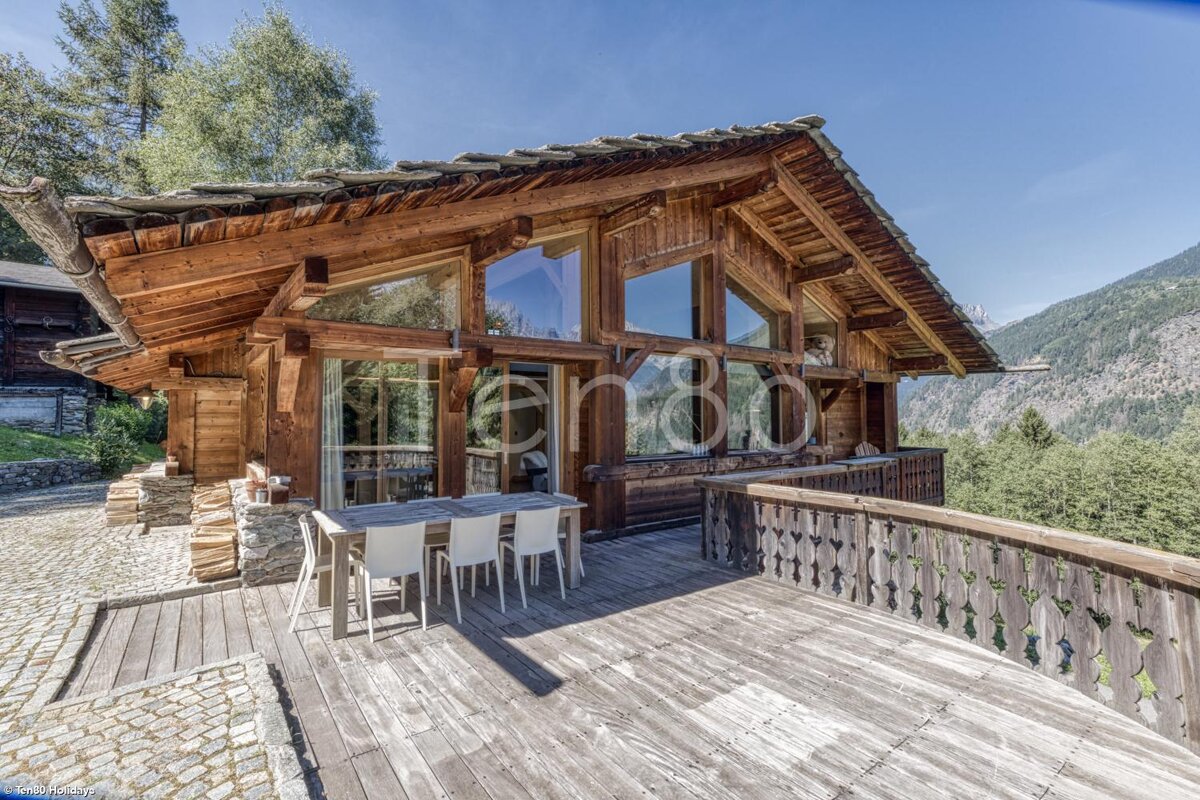 A large wooden house with a dining table and chairs in front of it