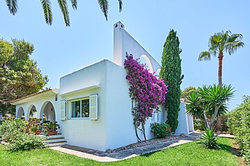 A white house with purple flowers and palm trees