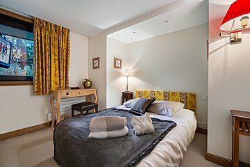 A bedroom with a bed a desk and a window