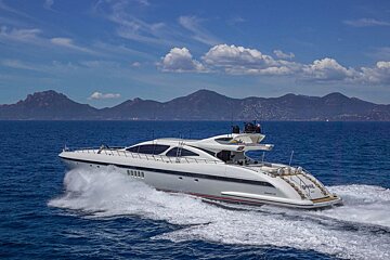 A large white yacht is floating in the ocean with mountains in the background
