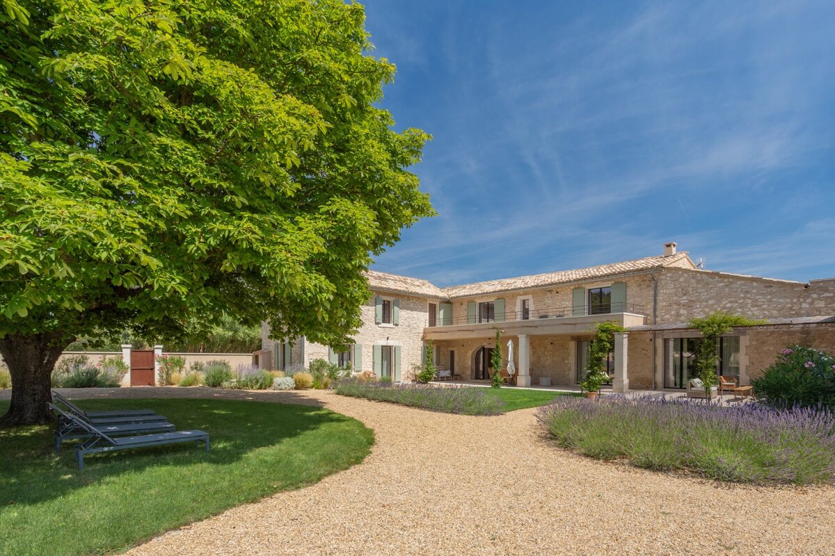 A large stone house with a gravel driveway leading to it