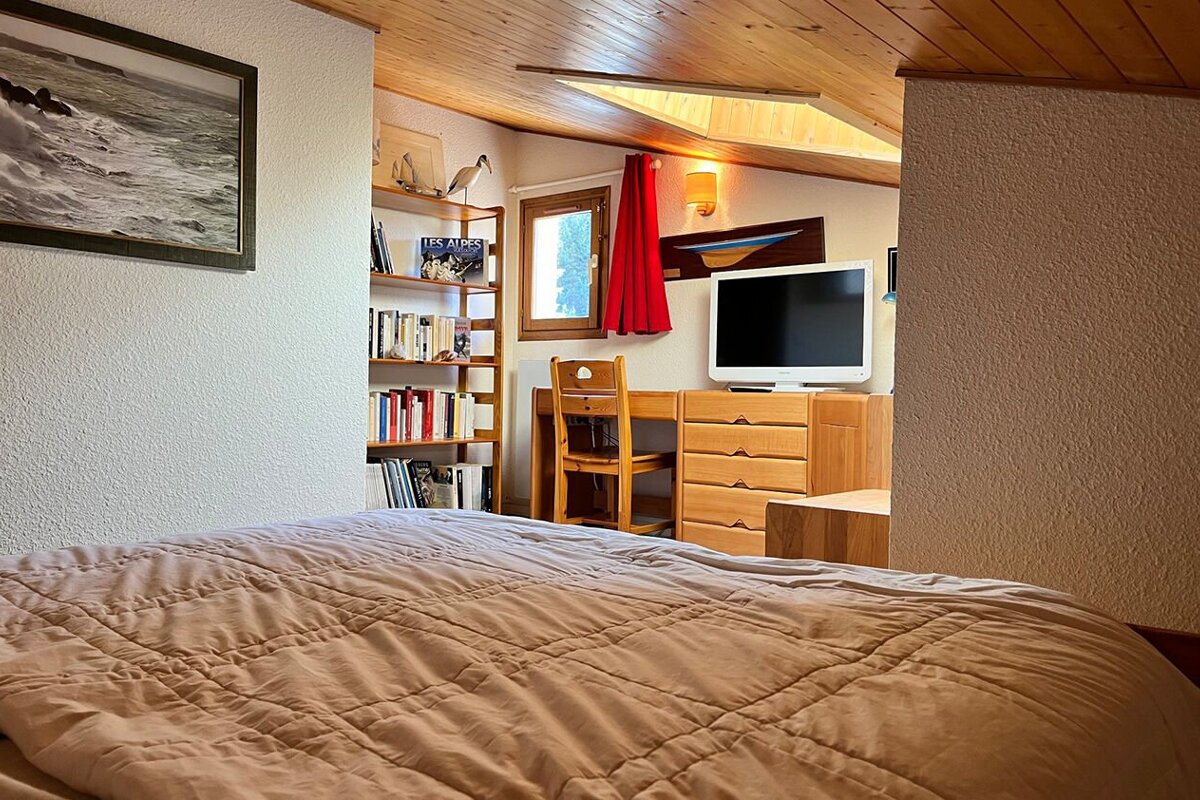 A bedroom with a bed a desk and a television