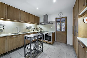 A kitchen with wooden cabinets and a clock on the wall