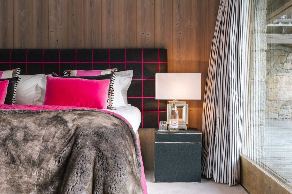 A bottle of evian water sits on a nightstand next to a bed