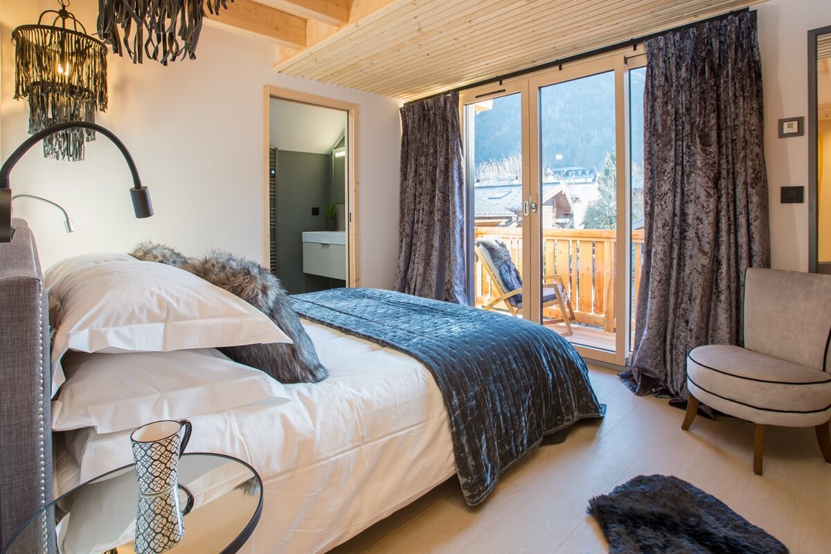 A bedroom with a large bed and a chair