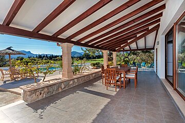 A patio with a table and chairs under a wooden roof