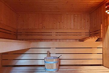 A wooden sauna with a bucket on the bench
