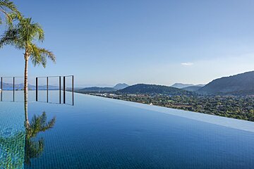 A swimming pool with mountains in the background and a palm tree in the foreground