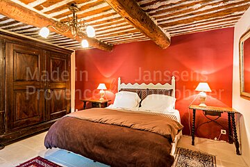 A bedroom with red walls and a bed that says made in provence