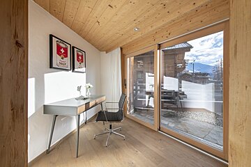 A room with a desk and a chair with a can of campbell 's soup on the wall