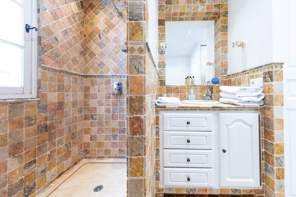 A bathroom with a walk in shower and a sink