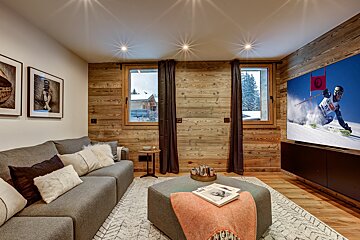 A couch and ottoman in a living room with a ski racer on the television