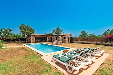 A row of white lounge chairs sit in front of a swimming pool