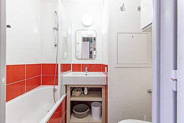 A bathroom with red and white tiles and a sink