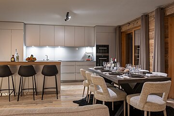 A kitchen with a table and chairs and a bottle of wine