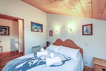 A bedroom with a bed and a picture of a mountain on the wall
