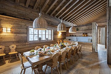 A dining room with a long wooden table and chairs