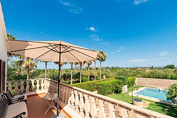 A balcony with a table and umbrella overlooking a swimming pool