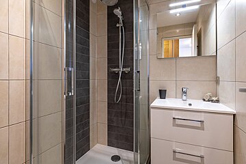 A bathroom with a walk in shower and a sink