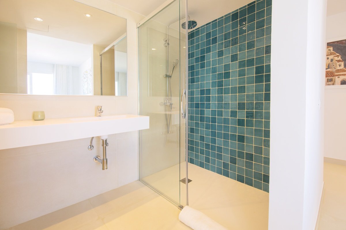 A bathroom with a walk in shower and a sink