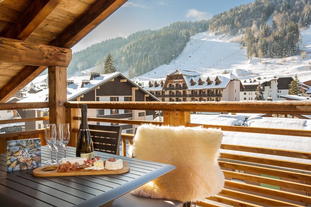 A bottle of champagne sits on a table in front of a ski resort